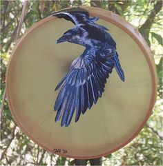 a blue bird painted on the side of a round object with trees in the background