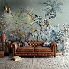 a couch sitting on top of a wooden floor in front of a wall with plants