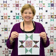 a woman holding up a piece of quilt