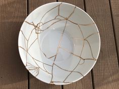 a white and gold plate on a wooden table with brown lines in the center,