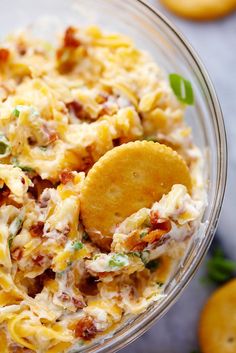 a glass bowl filled with pasta salad and a cracker on the side next to some lemons