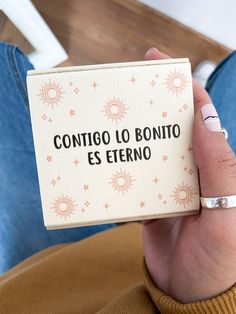 a person holding up a small card with the words contoo lo bonito esterno on it