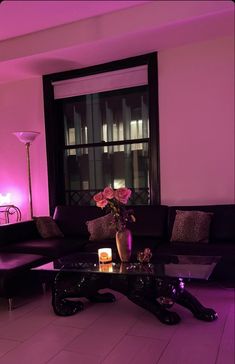 a living room filled with furniture next to a large window covered in pink lights and candles