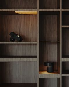 an empty shelf in a room with wooden shelves and black objects on it's sides