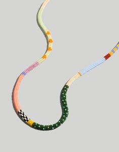 two necklaces with different colors and designs on each strand, one in the shape of a snake