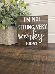 a wooden sign that says i'm not feeling very worky today next to a potted plant