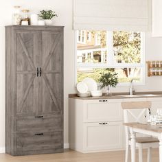 a kitchen with white walls and wooden floors, an open cabinet door is in the center of the room