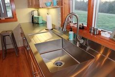 a stainless steel sink in a kitchen with wooden cabinets and counter tops next to a window