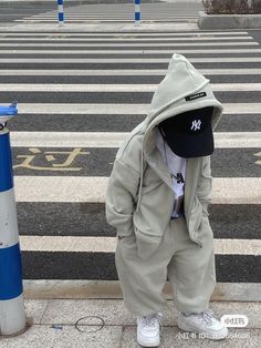 a little boy wearing a baseball cap standing in front of a blue and white striped crosswalk