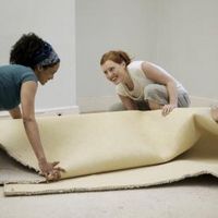 three women working on an area rug in a room