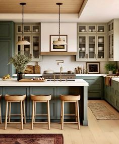 a kitchen with green cabinets and stools next to an island in front of the sink