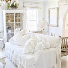 a white couch with ruffles on it in a living room next to a window