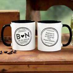 two black and white coffee mugs sitting next to each other on a wooden table