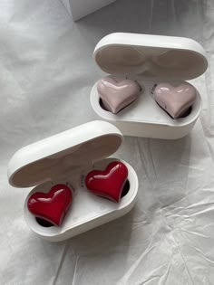 two heart shaped boxes sitting on top of a white sheet