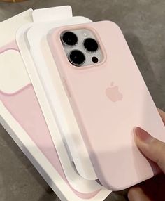 a person holding an iphone case in front of three other cases, one pink and the other white