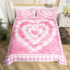 a bed with pink and white comforter in a room next to a plant on the floor