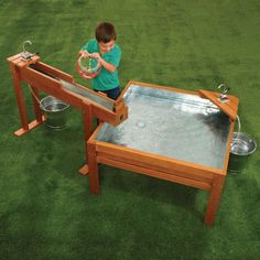 a young boy playing with a toy in an outdoor play area that is made out of wood and metal