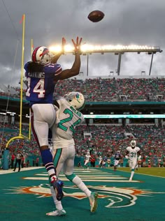 two football players are jumping up to catch the ball