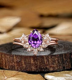 a ring with a purple stone surrounded by white diamonds on top of a piece of wood