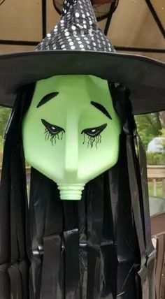 a green mask with black hair and a witch's hat on top of it