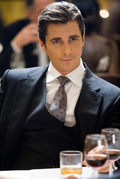 a man in a suit and tie sitting at a table with wine glasses on it