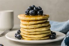 a stack of pancakes topped with blueberries and syrup