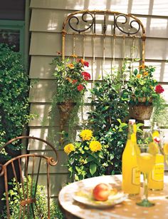 a table with two bottles of wine and some flowers on the side of a house