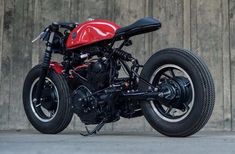 a red and black motorcycle parked in front of a wall