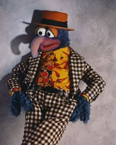 the puppet is wearing a top hat and checkered suit with an orange shirt on