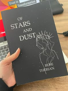 a person holding up a book with the title of stars and dust written on it