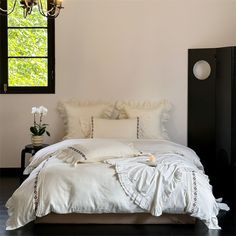 a bed with white linens and pillows in a room next to a black cabinet