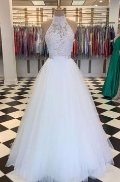 a white wedding dress on display in a store with black and white checkered flooring