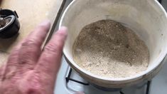 a man is standing in front of a pot on the stove and pointing at it