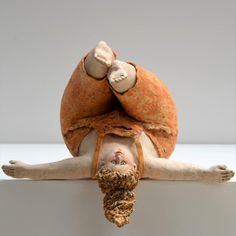 a sculpture of a man laying on top of a white surface with his arms and legs stretched out