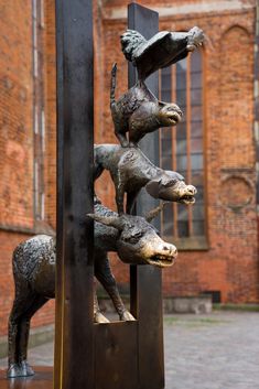 a metal sculpture with animals on it in front of a brick building