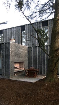 an outdoor fireplace is built into the side of a brick building next to a tree