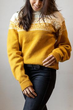 a woman wearing a yellow and white sweater with black jeans is smiling at the camera