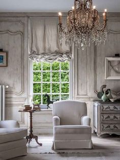 a living room filled with furniture and a chandelier hanging from the ceiling next to a window