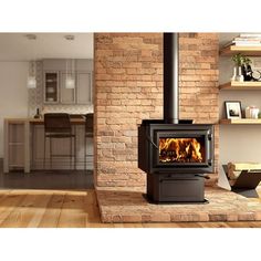 a wood burning stove sitting on top of a hard wood floor next to a brick wall