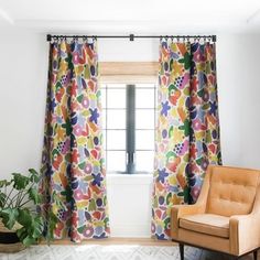 a chair sitting in front of a window next to a potted plant on top of a rug