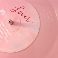 a pink record with the word love written on it's side and a small metal ball in the middle