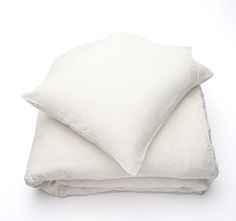 two white pillows are stacked on top of each other in front of a white background