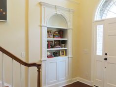 a white bookcase sitting in the corner of a living room next to a door