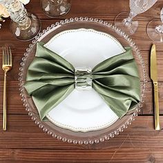 a table setting with silverware and green bow tie