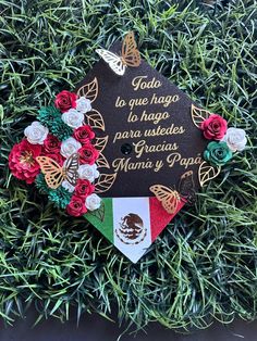 a graduation cap decorated with flowers on top of some green grass and butterflies in the background