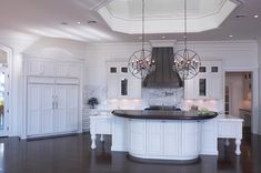 a large kitchen with white cabinets and black counter tops, an island in the middle