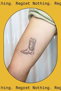 a small tattoo on the arm of a woman's leg with boots in it