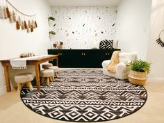 a black and white rug in a living room with two chairs, a table and potted plants