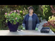 a woman standing in front of a table with potted plants