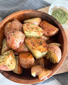 a wooden bowl filled with cooked potatoes and seasoning